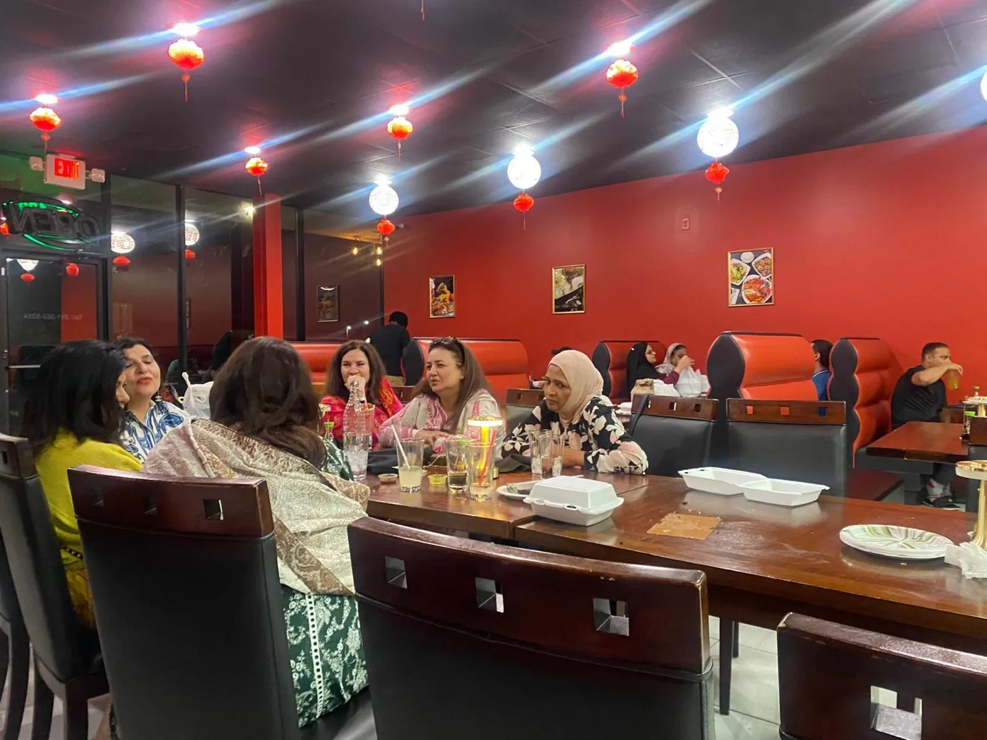 A large group seated together at the long table in the Wok & Karahi dining room
